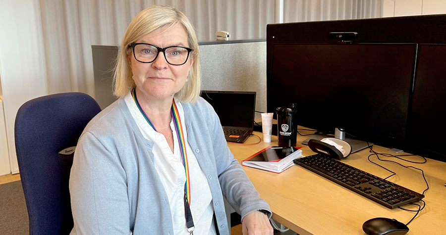 Sari Karlsson Manni sitter vid ett skrivbord på ett kontor. Hon tittar in i kameran och ser nöjd ut.
